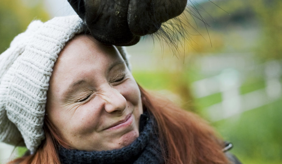 Kvinna rött långt hår och mössa och en hästmule