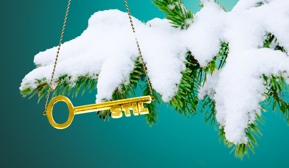 Gyllene nyckel med texten ‘STIL’ som hänger i en kedja från en snötäckt grangren mot en turkos bakgrund