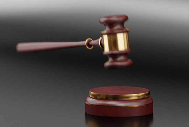 Ordförandeklubba i trä och mässing svävar över slagblock på mörk bakgrund.