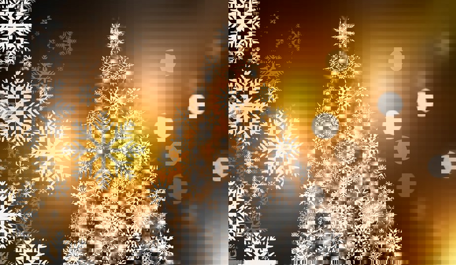 En julgran gjord av lysande vita snöflingor mot en varm, gyllene bakgrund med suddiga ljuspunkter.