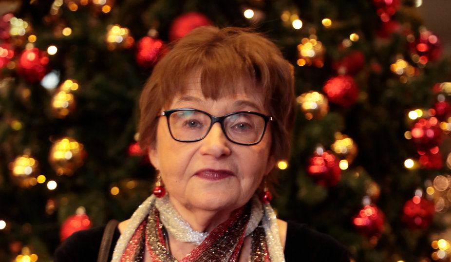 Kvinna framför julgran, håller rött hjärta.